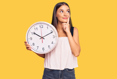 young,hispanic,woman,holding,big,clock,serious,face,thinking,about