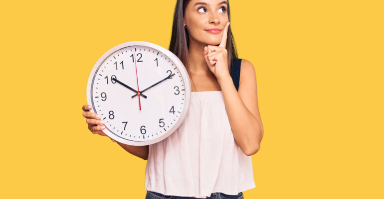 young,hispanic,woman,holding,big,clock,serious,face,thinking,about